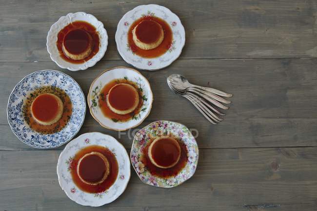 Top view of six plates with Creme caramel in sweet sauce on wooden surface — Stock Photo
