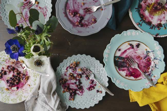 Top view of leftovers of blueberry pie on various plates and flowers — Stock Photo