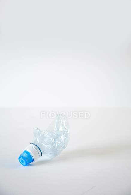 Erhöhte Ansicht der zerquetschten Wasserflasche auf weißer Oberfläche — Stockfoto