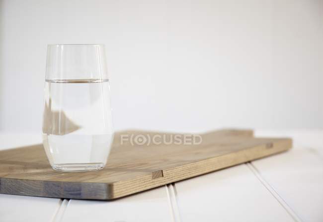 Vaso de agua en una tabla de cortar - foto de stock