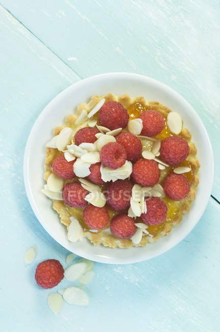 Raspberry tartlet with slivered almonds — Stock Photo