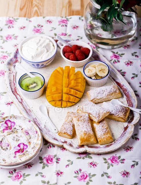 Повышенный вид пирожных с фруктами и взбитыми сливками — стоковое фото