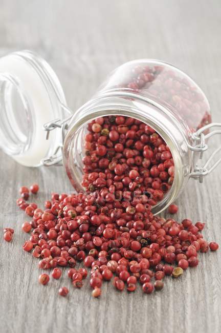 Pink peppercorns on wooden surface — Stock Photo