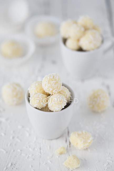 Vue rapprochée des truffes de noix de coco dans des tasses blanches — Photo de stock
