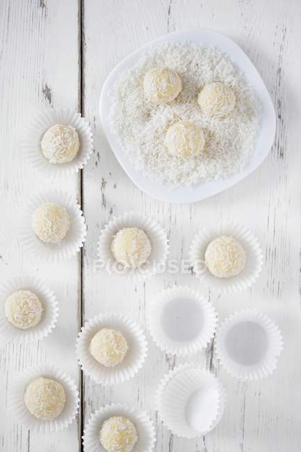 Top view of coconut truffles in flakes and in paper cups — Stock Photo