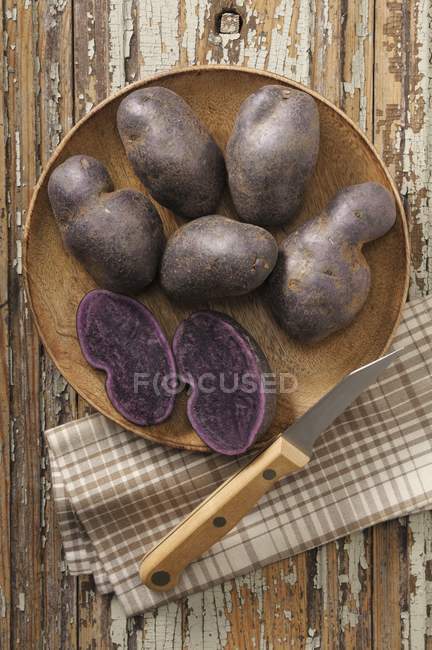 Purple potatoes with knife — Stock Photo