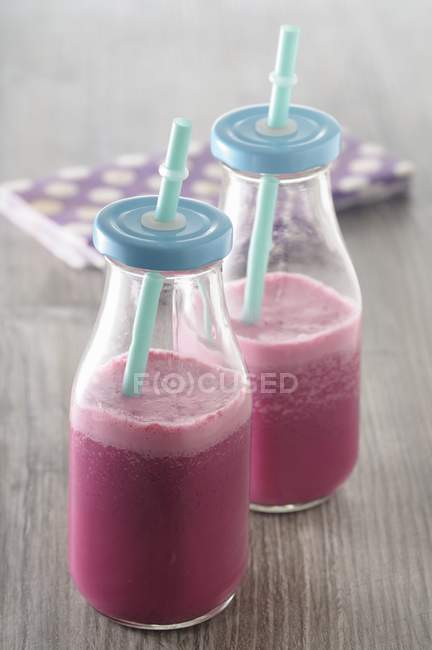 Beetroot smoothies in bottles with straws — Stock Photo