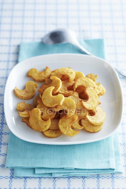 Тарелка чипсов в форме цыпочки на белой тарелке над голубым полотенцем — стоковое фото