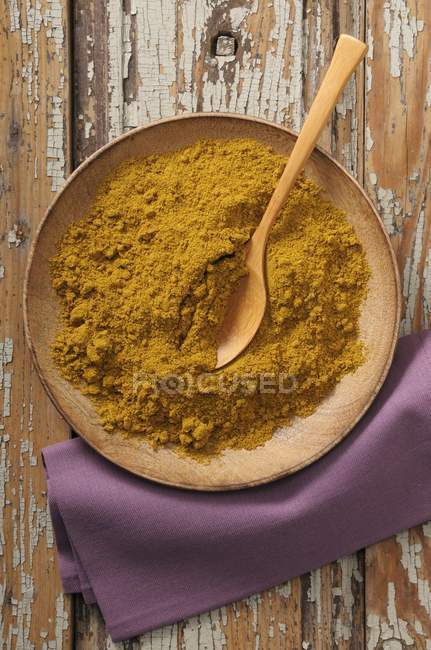 Curry powder with wooden spoon — Stock Photo