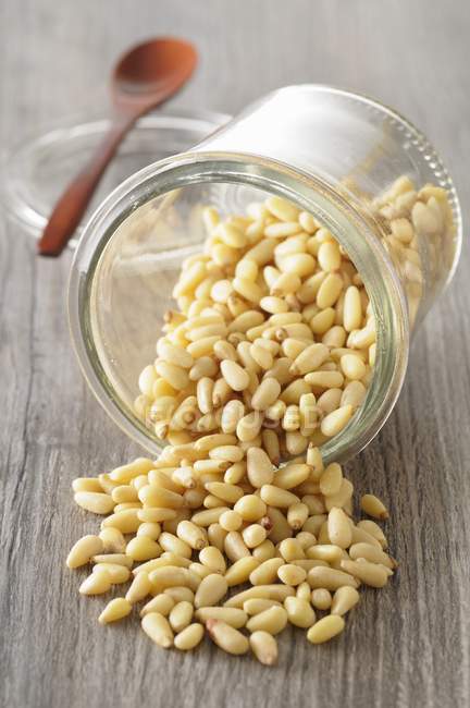 Pine nuts spilling from jar — Stock Photo