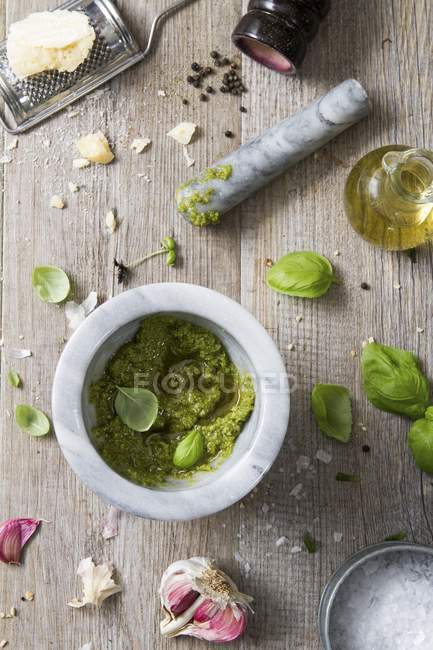 Top view of Pesto in a mortar with leaves, garlic, oil and bread around — Stock Photo