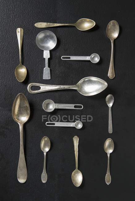 Vista dall'alto di una disposizione di vari cucchiai su una superficie nera — Foto stock
