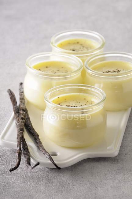 Primo piano vista di crema alla vaniglia e baccelli di vaniglia su tavola di porcellana — Foto stock