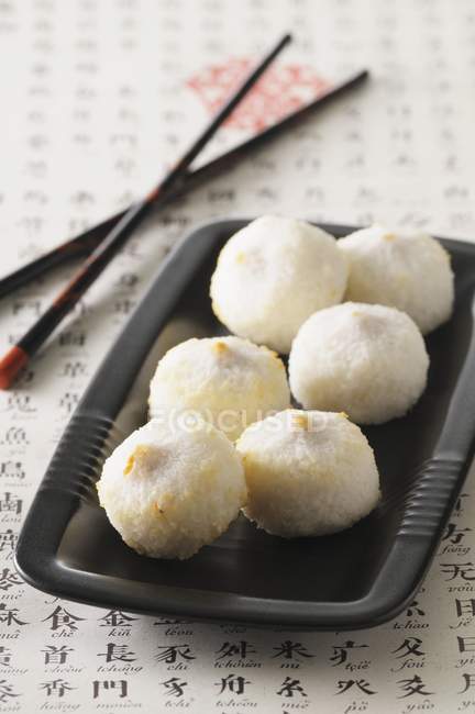 Closeup view of stuffed coconut balls on black dish — Stock Photo