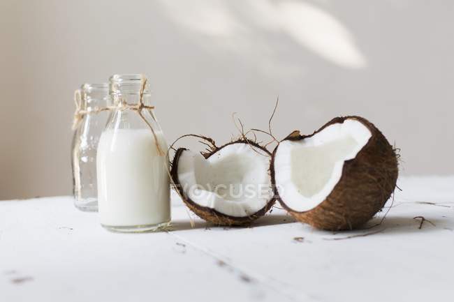 Geöffnete Kokosnuss und Flasche Milch — Stockfoto