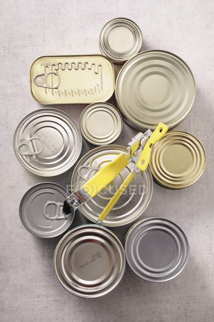 Vista superior de várias latas de comida com um abridor de lata — Fotografia de Stock