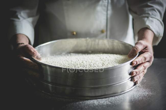 Vista ritagliata di un pasticciere con un grande setaccio di zucchero a velo — Foto stock