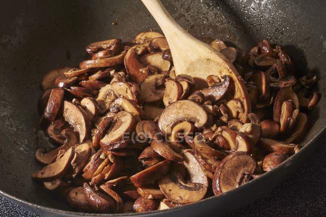 Faire frire les champignons avec de l'ail haché dans de l'huile d'olive dans un wok — Photo de stock