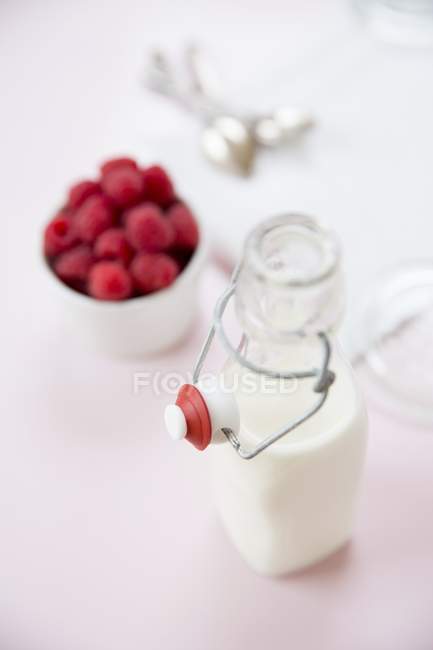 Bottle of milk and raspberries — Stock Photo