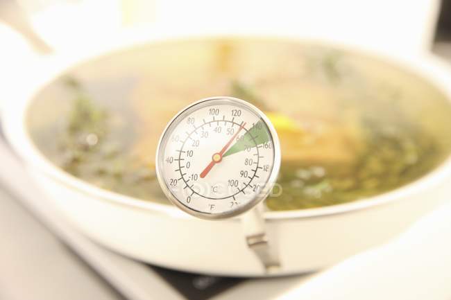 Closeup view of various herbs in oil with a thermometer — Stock Photo