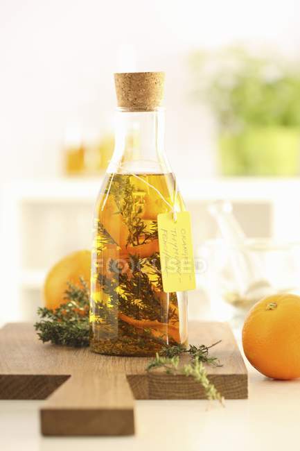 Óleo de ervas caseiro com tomilho e laranjas sobre mesa de madeira — Fotografia de Stock