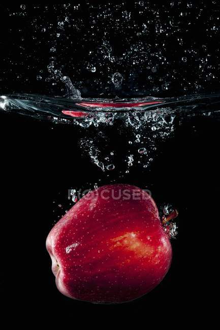 Maçã vermelha caindo na água — Fotografia de Stock