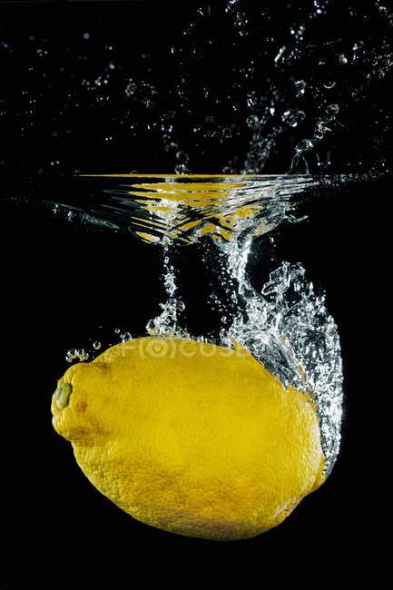 Лимон падает в воду — стоковое фото