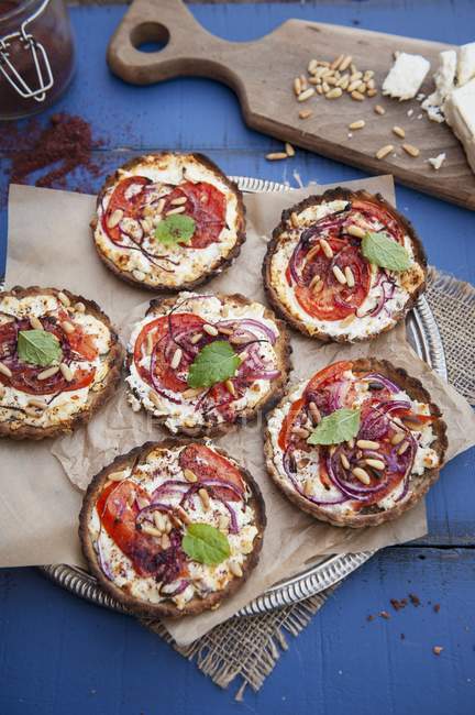 Tomato tarts on plate with baking paper and cloth over table — Stock Photo