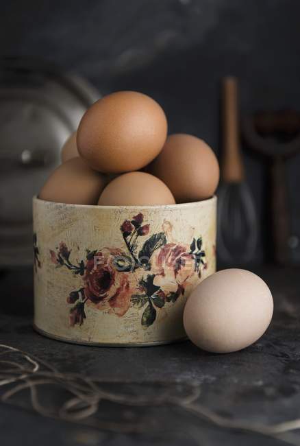 Huevos frescos en un recipiente con motivos de rosas - foto de stock