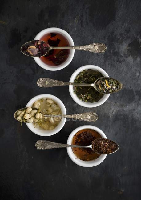 Vista superior de vários tipos de chá em colheres vintage sobre tigelas — Fotografia de Stock