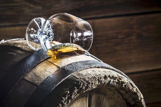 Glass of cognac on old wooden barrel — Stock Photo