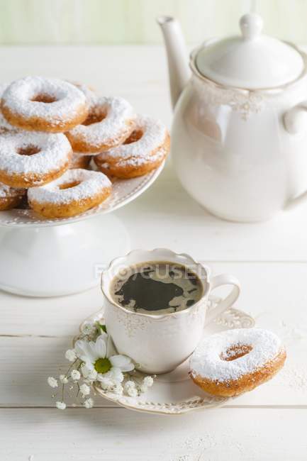 Пончики и кофе на белом столе — стоковое фото