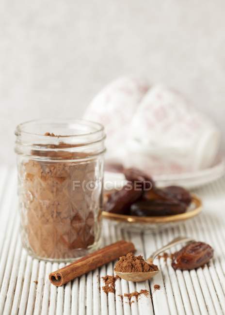 Vista de primer plano del cacao en polvo con dátiles y canela - foto de stock