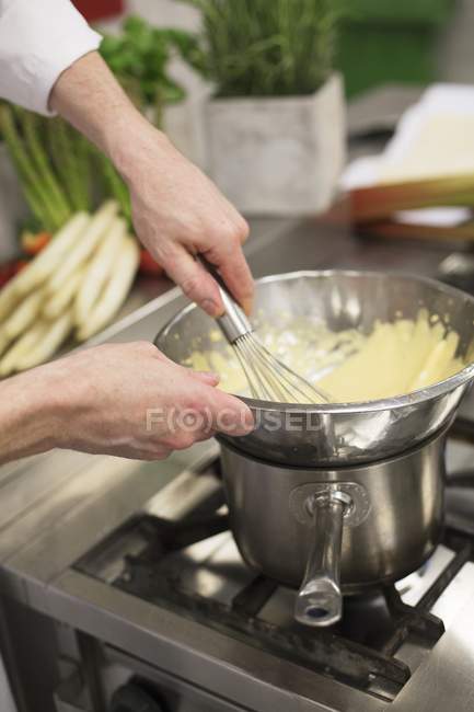 Vista ritagliata delle mani che mescolano la salsa di Bechamel in una ciotola con una frusta — Foto stock