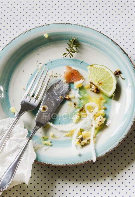 Vue surélevée d'une assiette avec couverts et restes de nourriture — Photo de stock