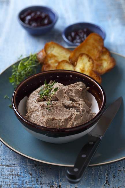 Foie pt avec pain grillé dans un bol sur une assiette avec couteau — Photo de stock