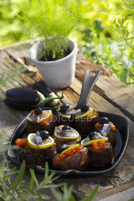 Auberginen la provenzalische auf schwarzem Teller über Holztisch im Freien mit Gras auf Hintergrund — Stockfoto