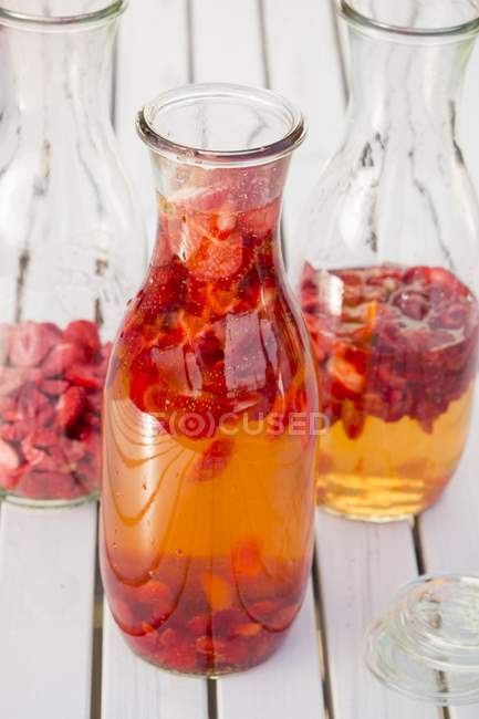 Vista close-up de morangos e vinagre em garrafas de preservação — Fotografia de Stock