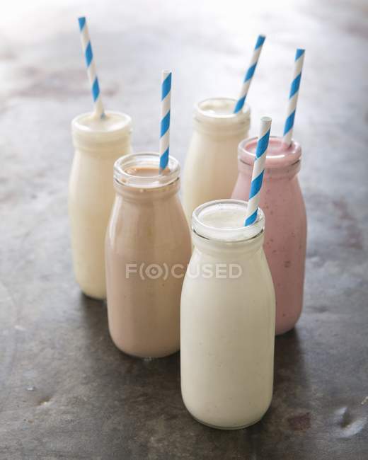 Différents milkshakes en bouteilles avec des pailles — Photo de stock
