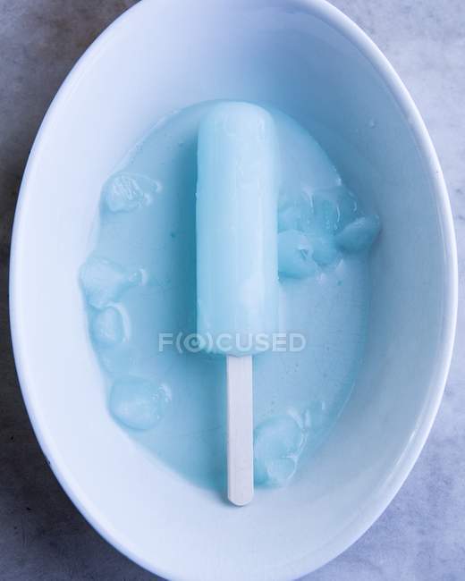 Primer plano vista superior de lolly de hielo azul en tazón blanco - foto de stock