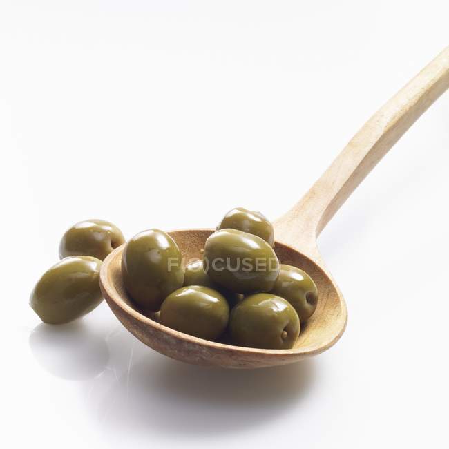 Зеленые оливки с деревянной ложкой — стоковое фото