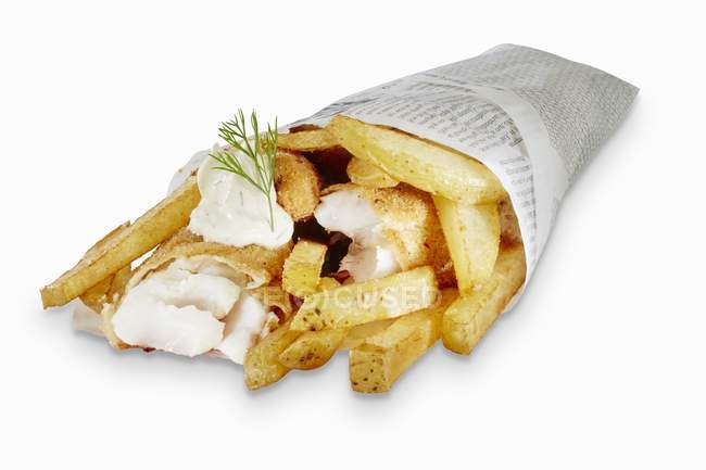 Vista de primer plano de pescado y patatas fritas envueltas en periódico - foto de stock