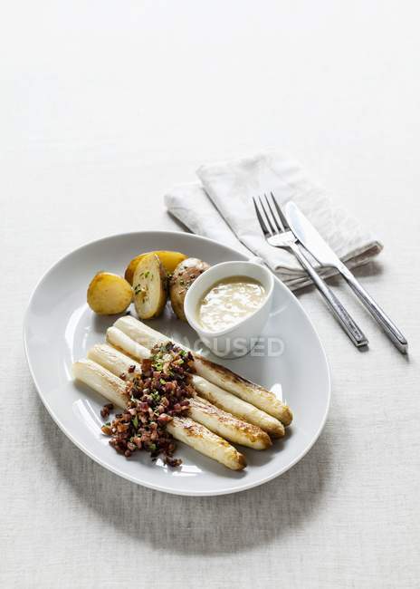Espargos brancos com bacon em cubos fritos, cebolinha, molho holandês e batatas — Fotografia de Stock