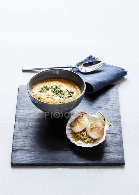 Повышенный вид пенного томата и фенхелевого супа с луком и жареными гребешками — стоковое фото