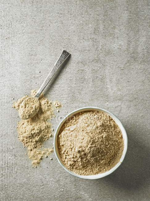 Maca powder in a bowl and on a silver spoon — Stock Photo