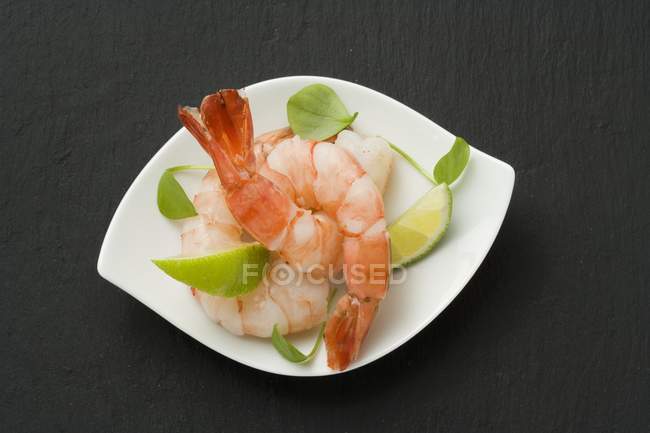 Crevettes pelées bouillies avec des coins de citron vert — Photo de stock