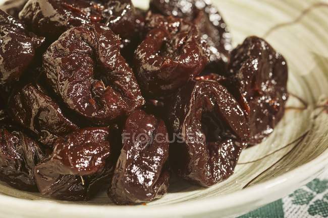 Whole dried plums, pitted  on white plate — Stock Photo