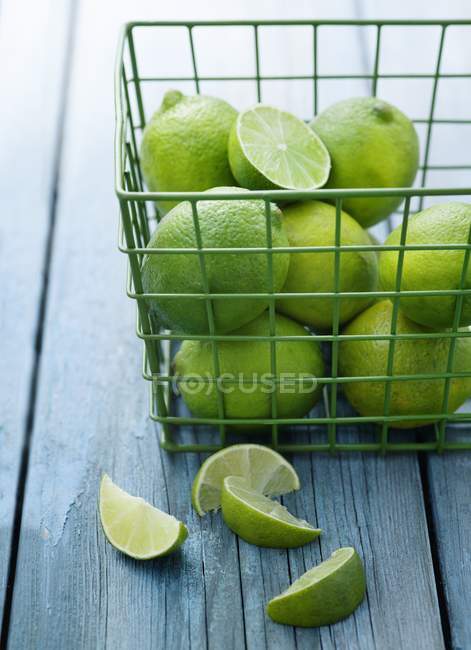 Limes in green wire basket — Stock Photo