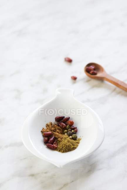 Closeup view of a bowl of spices with a spoon on a marble surface — Stock Photo