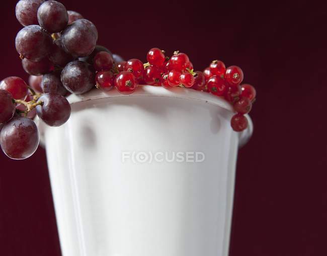 Groselhas vermelhas e uvas na xícara — Fotografia de Stock